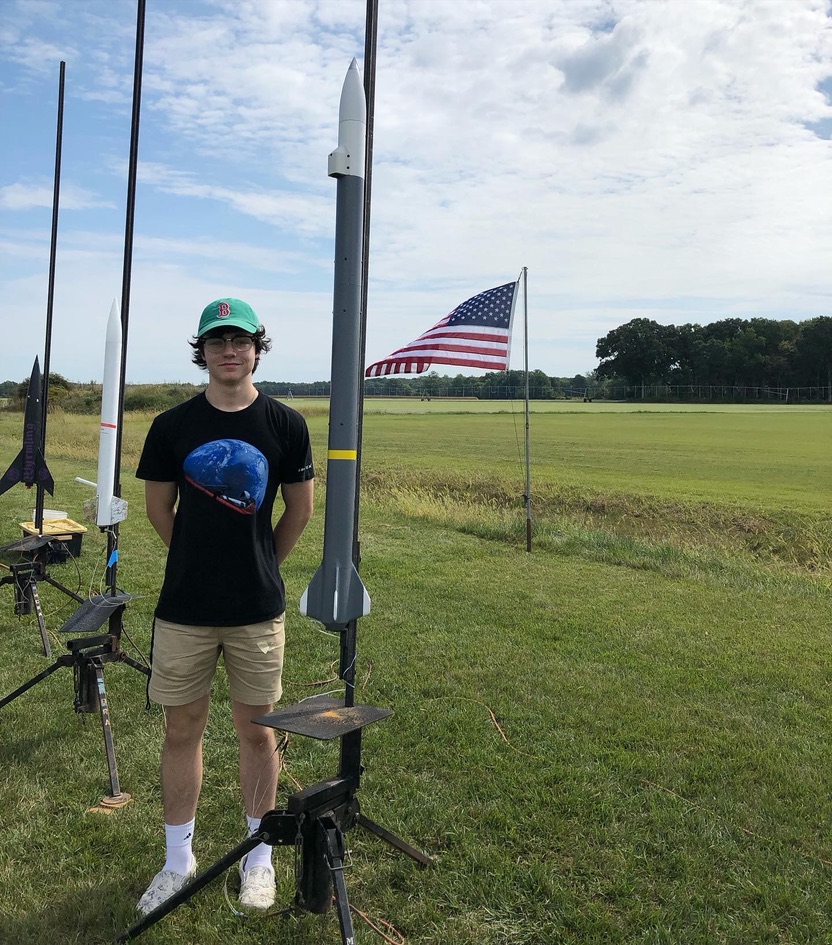 Adam Pouliot standing beside his Level 1 certification rocket on the launch pad